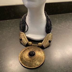Brass medallion suspended by glossy black beads